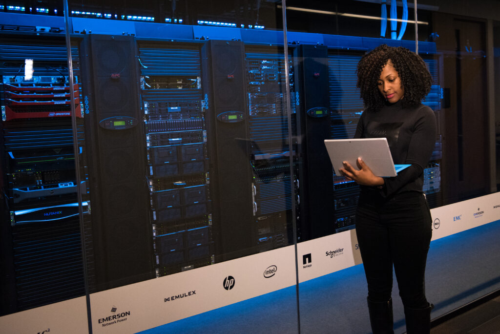 Software engineer standing beside server racks